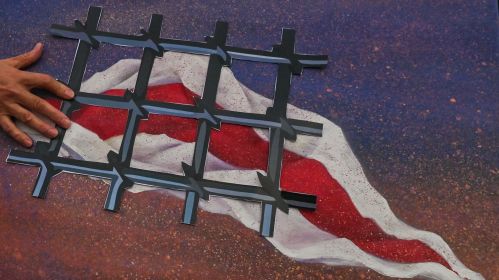 Пратэстоўца трымае сімвалічную папяровую турэмную рашотку, якая сімвалізуе беларускае насельніцтва ў турмах і адсутнасць свабоды ў Беларусі. Кракаў, Малапольскае ваяводства, Польшча. 9 жніўня 2022 года. Фота: Artur Widak / NurPhoto via Getty Images