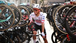 Rafał Majka (fot. Getty Images)  Zdjęcie uśmiechniętego kolarza Rafała Majki, ubranego w biało-czerwony strój zespołu UAE Team Emirates i kask. Kolarz podnosi prawą dłoń w geście pozdrowienia. Rafał Majka, jeden z najlepszych polskich kolarzy w historii, zakończył karierę po ostatnim starcie w wyścigu Il Lombardia. (fot. Getty Images)
