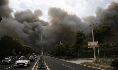 Grecja, 23 lipca 2018 r. Dym unosi się nad aleją podczas pożaru lasu w Neo Voutsa, na północno-wschodnim przedmieściu Aten. Fot. PAP/EPA / ALEXANDROS VLACHOS