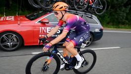 Stanisław Aniołkowski (fot. Getty Images) Zdjęcie przedstawia jednego z polskich kolarzy podczas rywalizacji, dynamicznie pokonującego kolejne kilometry wyścigu na tle samochodu zespołu INEOS Grenadiers.