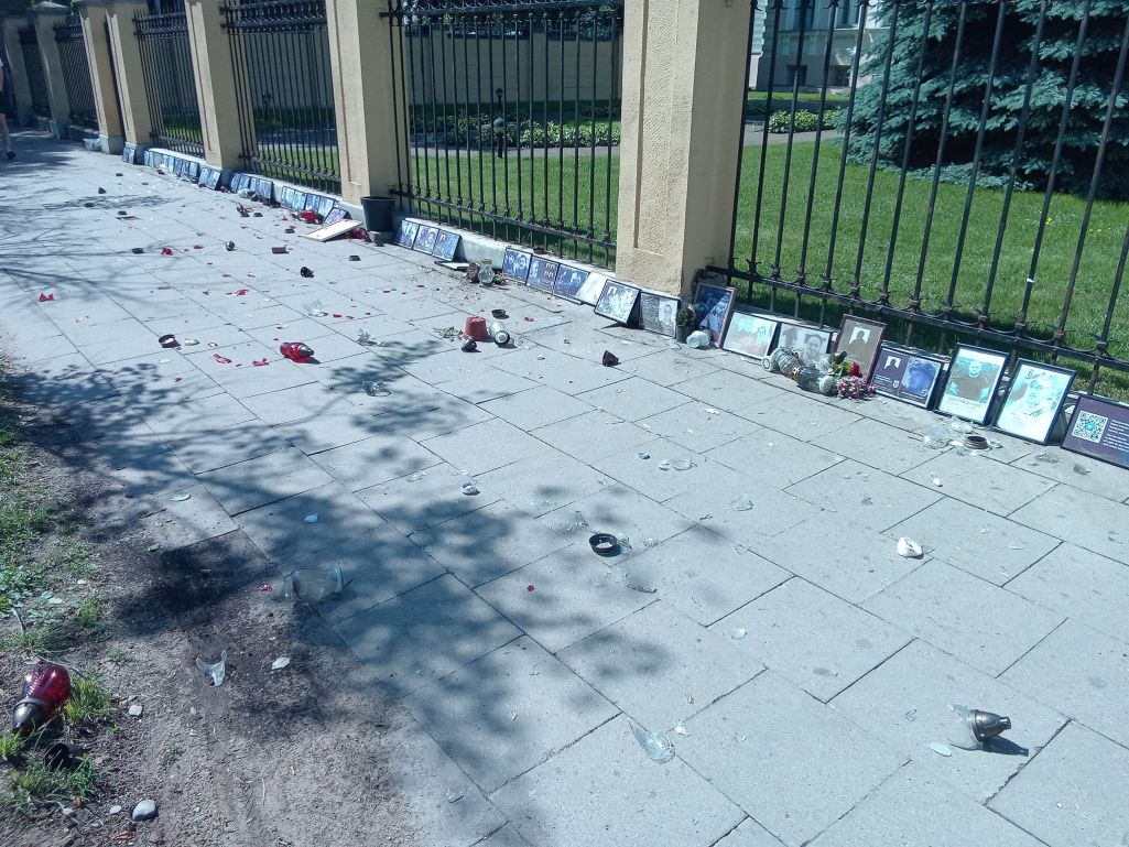 Невядомы мужчына раскідаў нагамі знічы і партрэты рэпрэсаваных ля амбасады Беларусі ў Вільні. (Фота: Ілля Міронаў / Facebook)