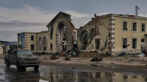 Вайсковая машына праязджае міма разбуранага чыгуначнага вакзалу ў Канстанцінаўцы, Данецкая вобласць, Украіна. 16 чэрвеня 2025 года. Фота: Kostiantyn Liberov / Libkos / Getty Images