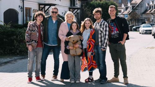 Aktorzy serialu „Rodzinka.pl” podczas wspólnego dnia zdjęciowego. Na fotografii widoczna jest obsada: Mateusz Pawłowski, Tomasz Karolak, Małgorzata Kożuchowska, Emma Pokromska, Olga Kalicka, Maciej Musiał i Adam Zdrójkowski. Cała serialowa rodzina Boskich pozuje razem na ulicy, uśmiechnięta i pełna pozytywnej energii.