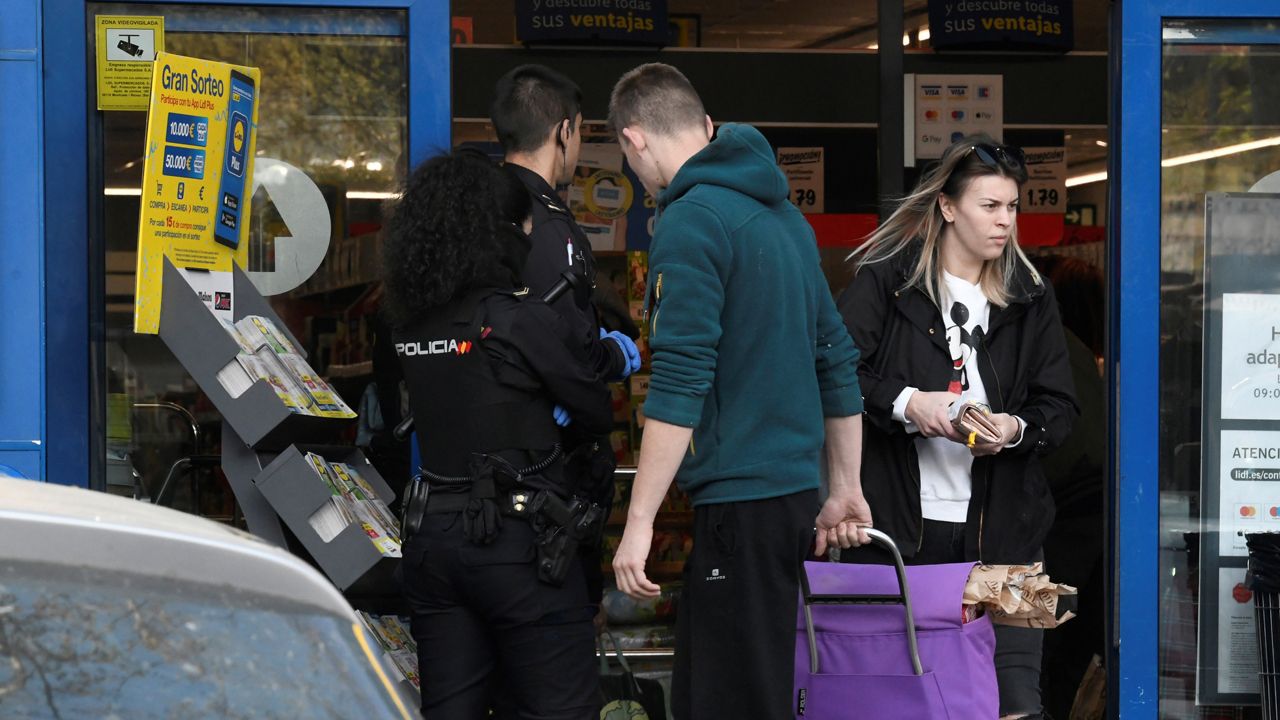 Funkcjonariusze policji próbują uspokoić klientów sklepu spożywczego w Madrycie (fot. PAP/EPA/VICTOR LERENA)
