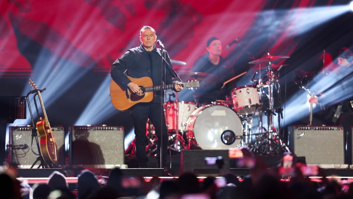 Bryan Adams śpiewa i gra na gitarze. Na zdjęciu widać też perkusistę.