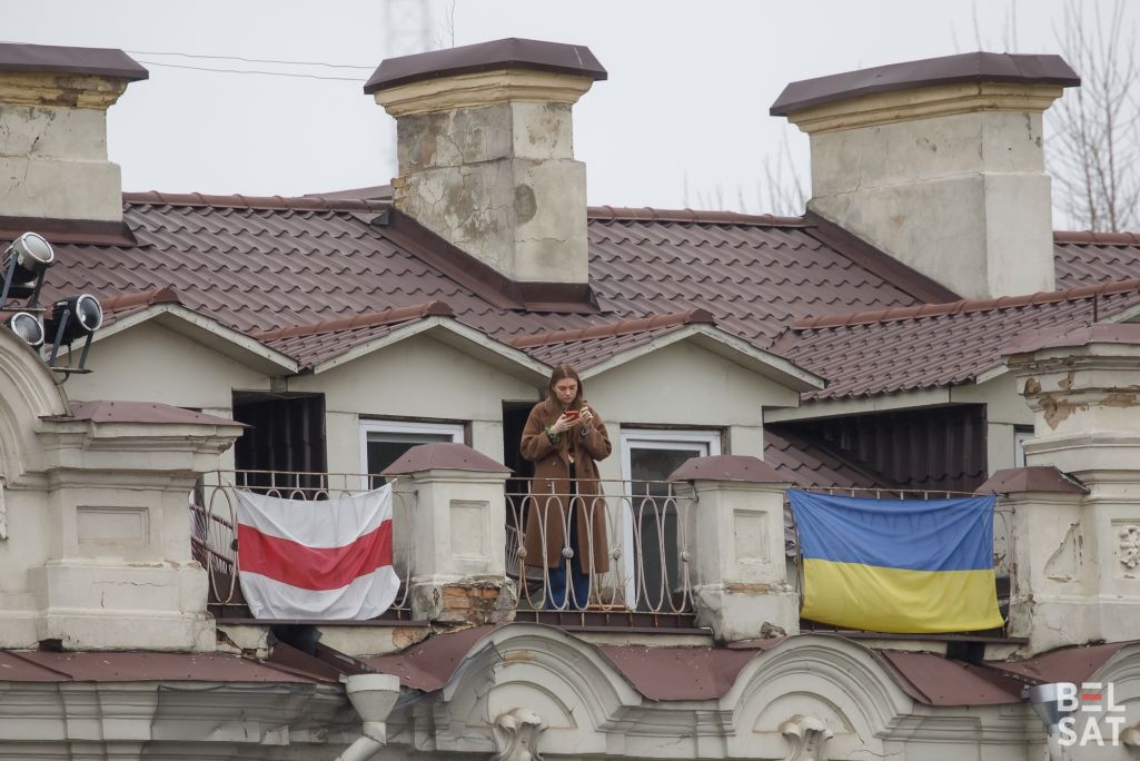 Здымак мае ілюстрацыйны характар. Дзяўчына стаіць на балконе паміж сцягамі Беларусі і Украіны на праспекце Гедыміна. Вільня, Літва. 21 лютага 2024 года. (Фота: Белсат)