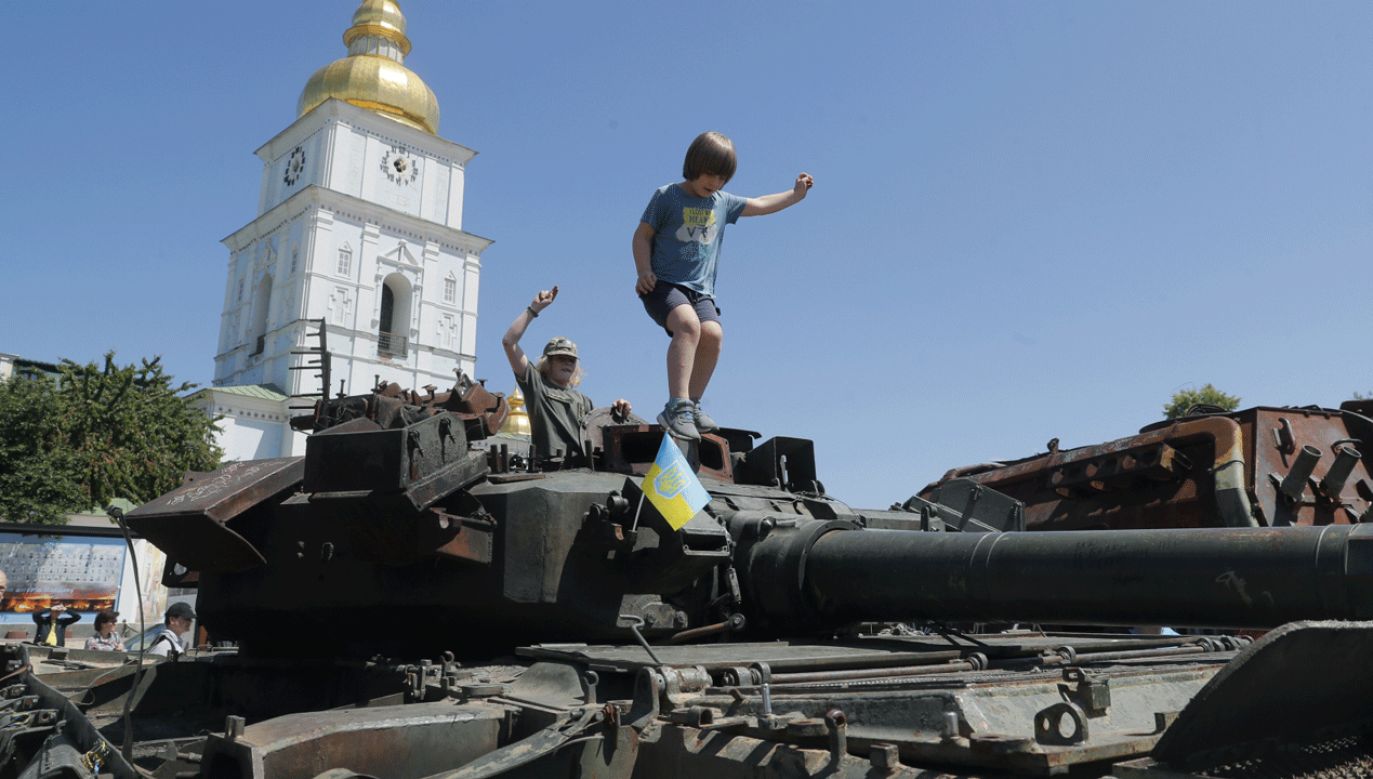 Ukraińskie dzieci bawiące się na zniszczonym rosyjskim czołgu; Kijów (fot. PAP/EPA/SERGEY DOLZHENKO)
