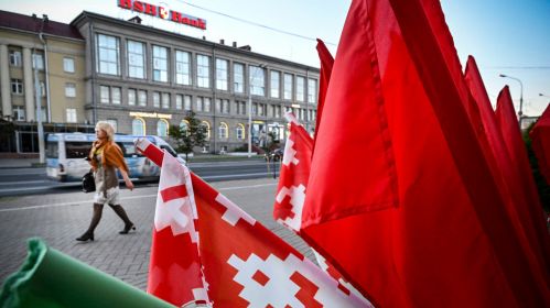 Жанчына праходзіць міма ўстаноўкі з дзяржаўнымі сцягамі ў цэнтры Менску, Беларусь. 20 ліпеня 2022 года. Здымак мае ілюстрацыйны характар. Фота: Alexander Nemenov / AFP / East News